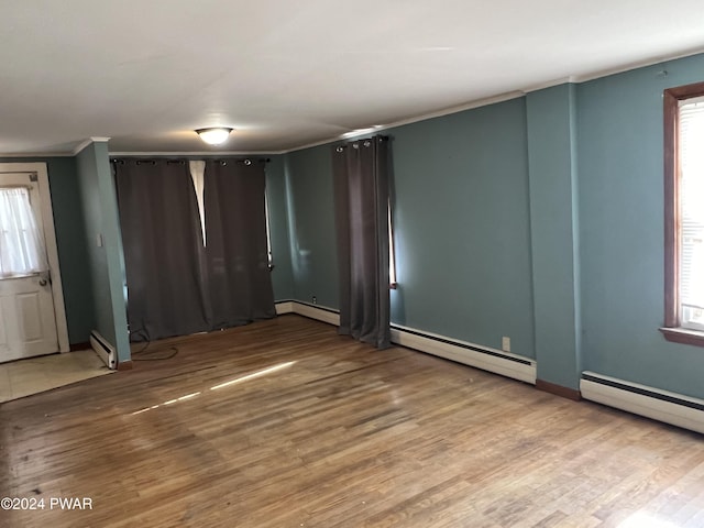 unfurnished room featuring a baseboard radiator, a baseboard heating unit, wood finished floors, and ornamental molding