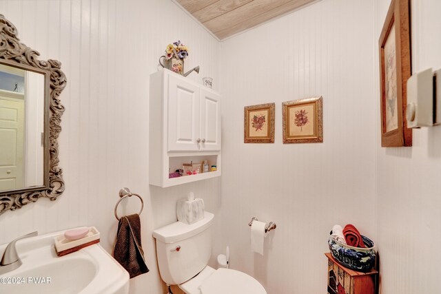 bathroom with toilet, wood ceiling, and sink