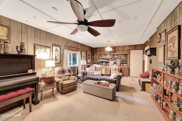 carpeted living room with ceiling fan and wooden walls