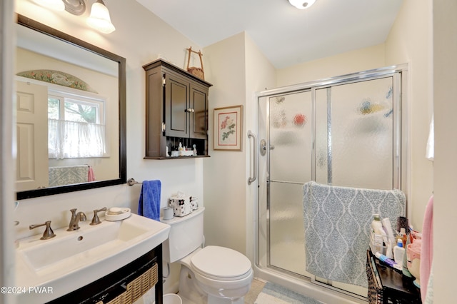 bathroom featuring vanity, toilet, and a shower with door