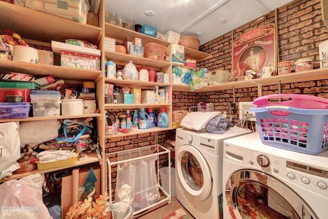 laundry area with washer and clothes dryer and brick wall