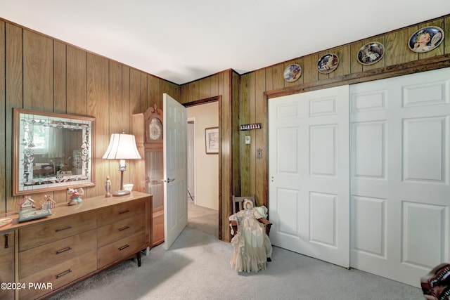 carpeted bedroom featuring a closet and wood walls