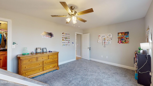 carpeted bedroom with ceiling fan, a walk in closet, and a closet