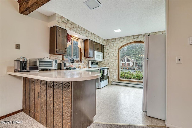 kitchen featuring kitchen peninsula, a textured ceiling, white appliances, and a healthy amount of sunlight