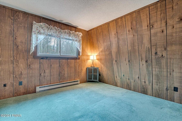 carpeted spare room featuring wood walls, a textured ceiling, and a baseboard radiator