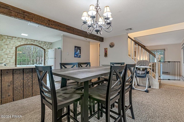 dining room featuring beamed ceiling, a textured ceiling, light carpet, and a chandelier