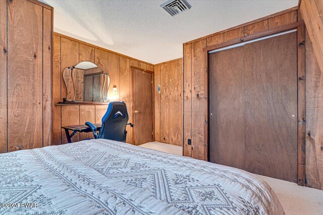 bedroom featuring wooden walls, a closet, and a textured ceiling