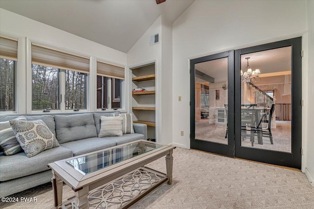 carpeted living room with built in shelves, a chandelier, and lofted ceiling