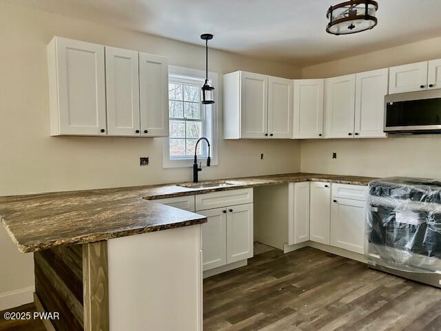 kitchen with sink, decorative light fixtures, and white cabinetry