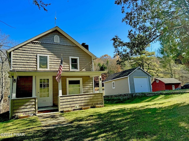 back of house featuring covered porch, an outbuilding, and a yard