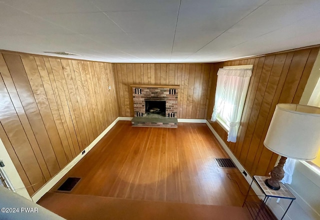 unfurnished living room with wood walls, a fireplace, and wood-type flooring