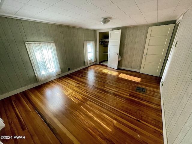 unfurnished bedroom with a closet and wooden walls