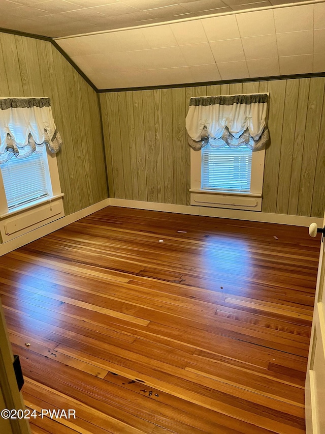 additional living space with hardwood / wood-style flooring, wood walls, and lofted ceiling