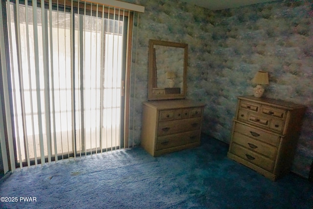 unfurnished bedroom with dark colored carpet, multiple windows, and wallpapered walls