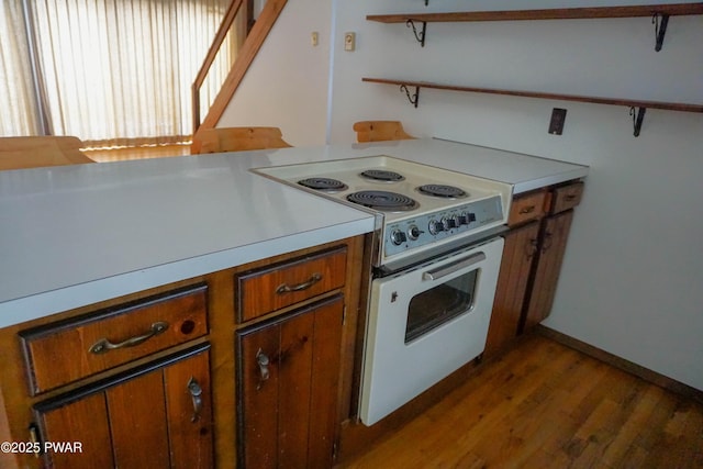 kitchen featuring light wood-style floors, light countertops, open shelves, brown cabinetry, and white electric range oven