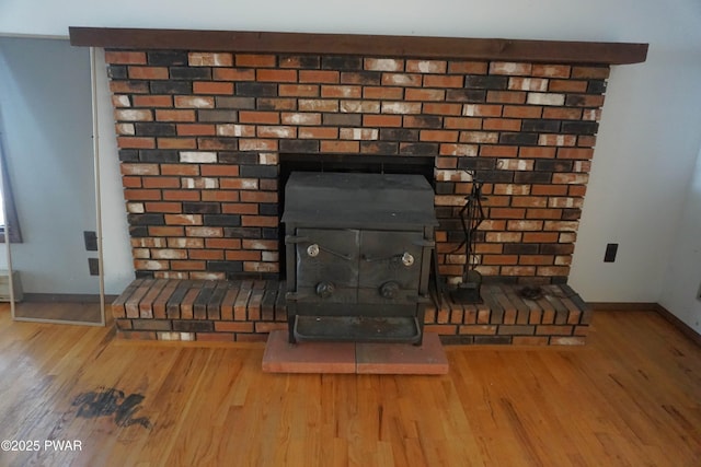 room details featuring wood finished floors, a wood stove, and baseboards