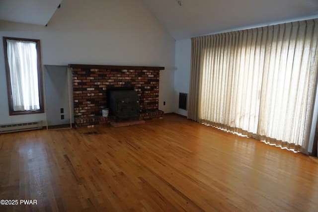 unfurnished living room featuring a baseboard heating unit, high vaulted ceiling, and wood finished floors