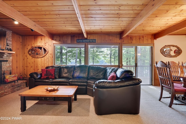 carpeted living room featuring beamed ceiling, wood walls, wood ceiling, and a brick fireplace