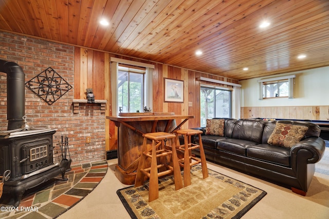 carpeted living room with wood walls, a wood stove, brick wall, and bar area