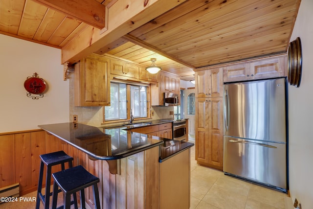 kitchen with a kitchen breakfast bar, kitchen peninsula, stainless steel appliances, and a baseboard radiator