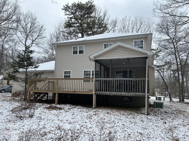 snow covered property featuring a wooden deck and a sunroom