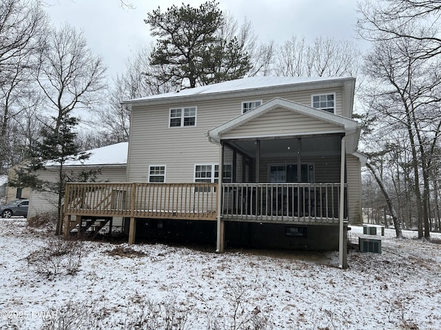 snow covered property featuring a wooden deck and a sunroom