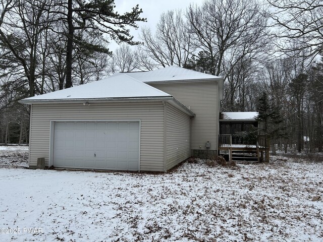 view of snow covered exterior with a garage and a sunroom