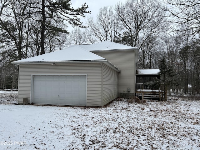 view of snow covered exterior with a garage and a sunroom