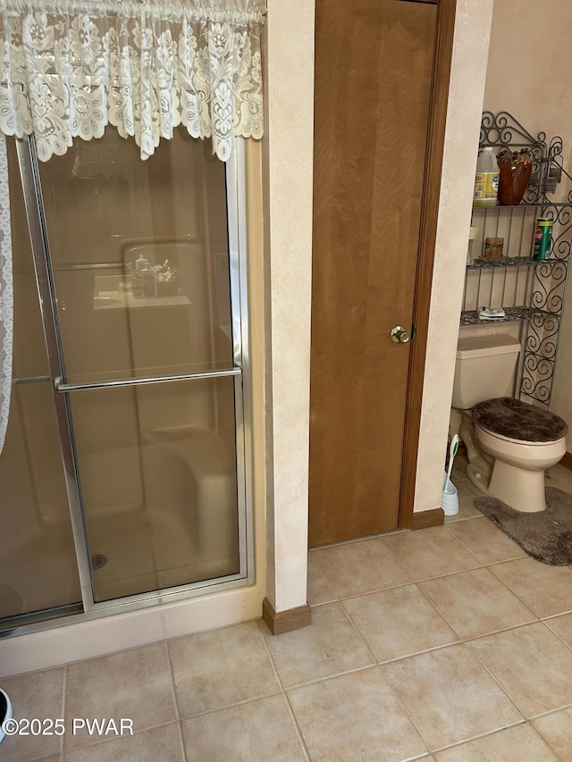 bathroom with tile patterned flooring, toilet, and walk in shower