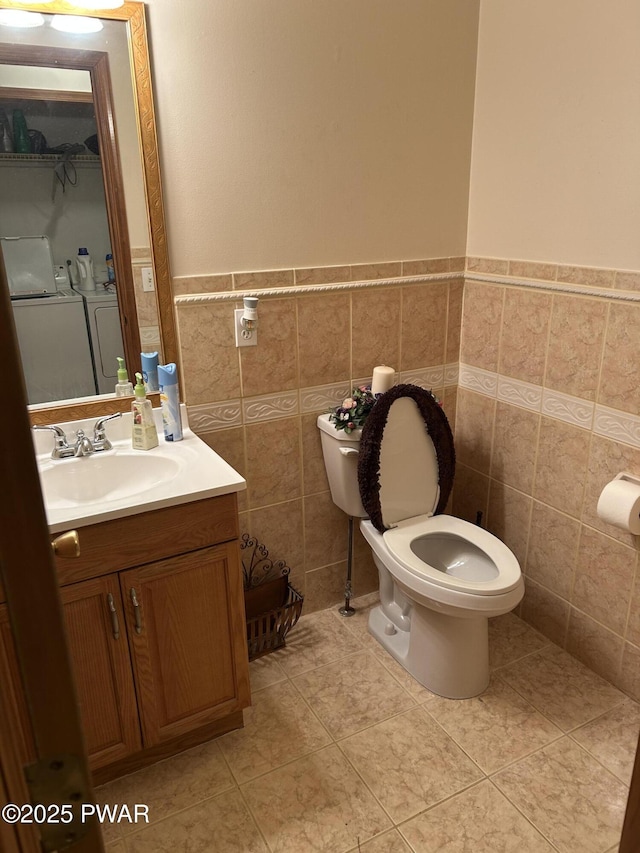 bathroom with vanity, washer and dryer, tile walls, tile patterned flooring, and toilet