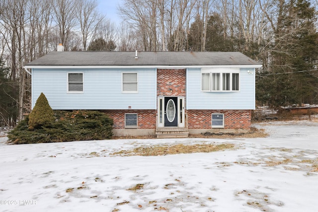 raised ranch featuring entry steps, brick siding, and a chimney