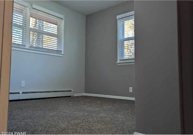 carpeted empty room featuring a baseboard heating unit