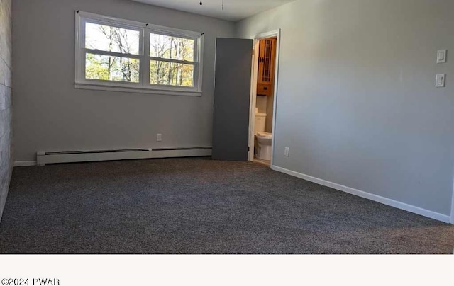 carpeted empty room featuring a baseboard heating unit