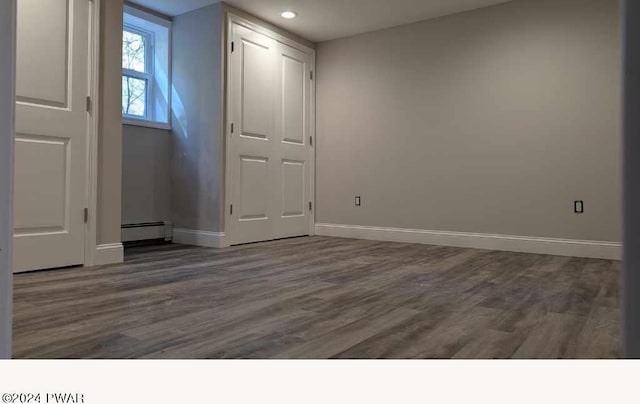 empty room with dark wood-type flooring and a baseboard radiator