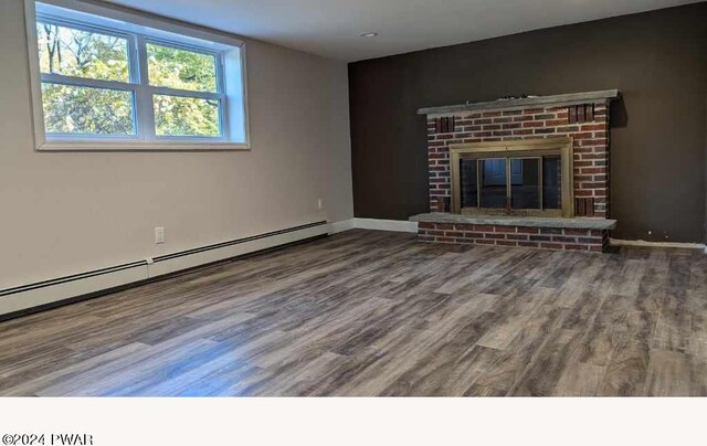 unfurnished living room with baseboard heating, a fireplace, and wood-type flooring