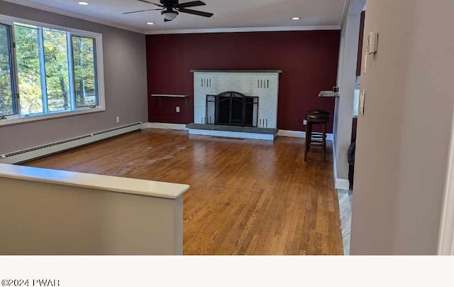 unfurnished living room with ceiling fan, a brick fireplace, ornamental molding, a baseboard heating unit, and hardwood / wood-style flooring