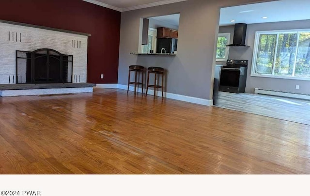 unfurnished living room with a brick fireplace, light hardwood / wood-style floors, ornamental molding, and a baseboard heating unit