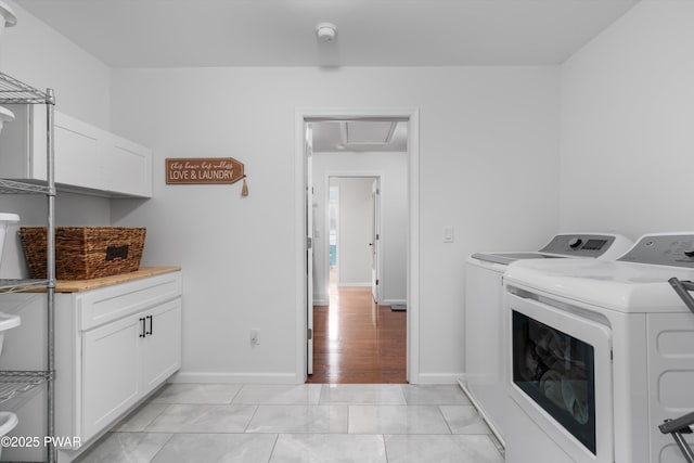 laundry area with cabinets, light tile patterned floors, and independent washer and dryer