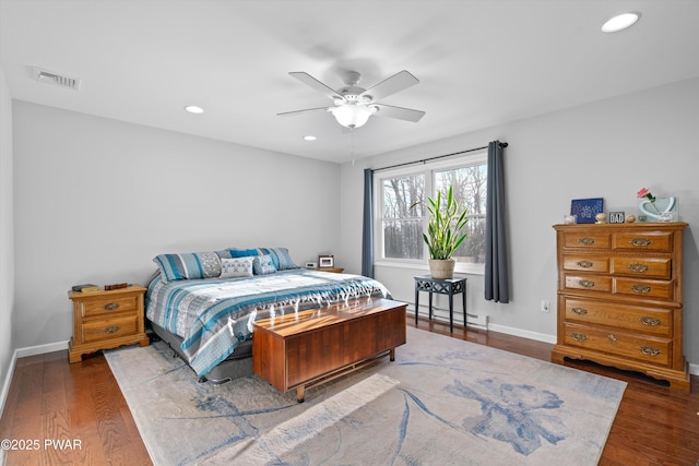 bedroom with ceiling fan, a baseboard heating unit, and dark hardwood / wood-style floors