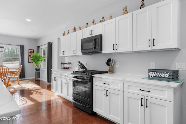 kitchen with gas range, dark wood-type flooring, light stone countertops, and white cabinets