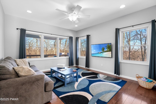 living room with dark wood-type flooring, ceiling fan, and plenty of natural light