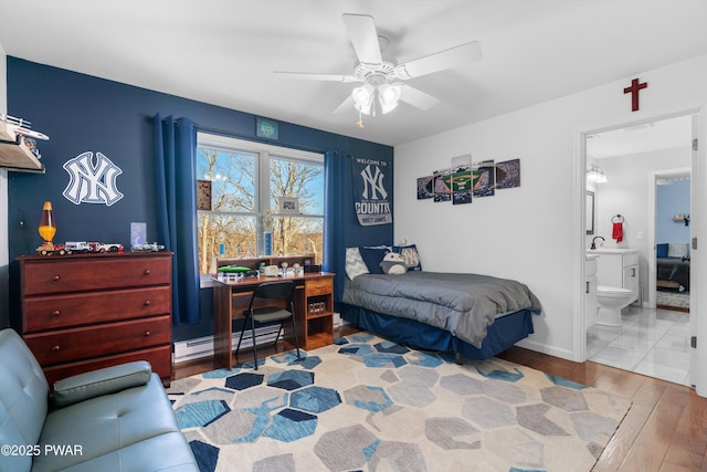 bedroom with sink, ensuite bath, ceiling fan, baseboard heating, and hardwood / wood-style floors