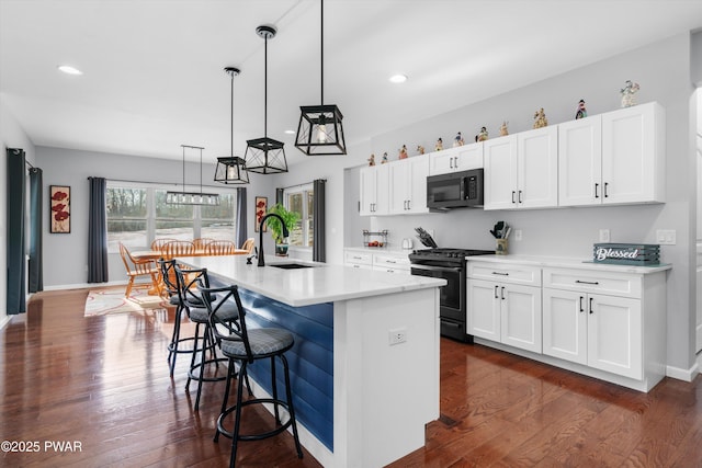 kitchen with sink, decorative light fixtures, a center island with sink, range with gas stovetop, and white cabinets