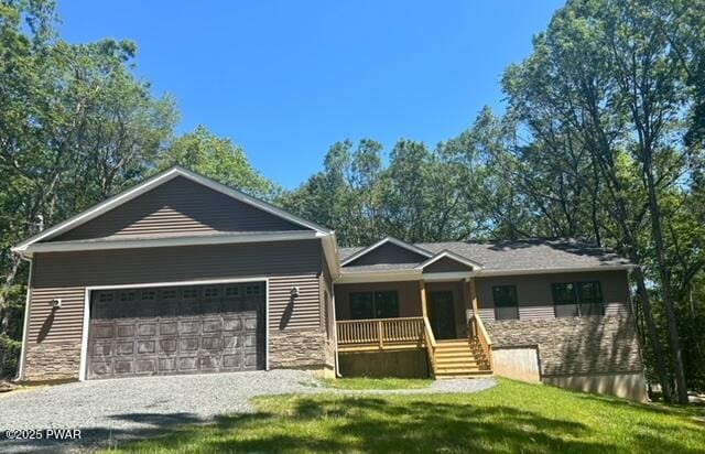 119 Lenape Dr, Milford, PA 18337 - view of front of home with covered porch, gravel driveway, an attached garage, a front yard, and stone siding