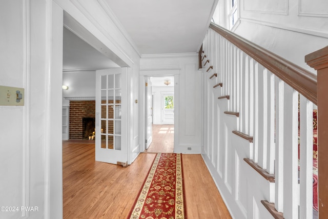 foyer entrance featuring a fireplace, light wood-type flooring, and crown molding