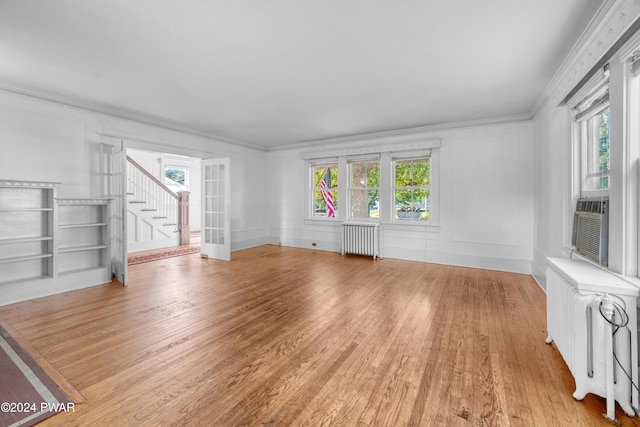 unfurnished living room featuring a wealth of natural light, crown molding, and radiator