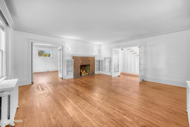 unfurnished living room featuring ornamental molding, light hardwood / wood-style flooring, and a brick fireplace