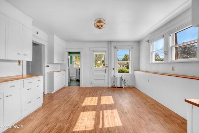 kitchen with white cabinetry, radiator heating unit, plenty of natural light, and light wood-type flooring