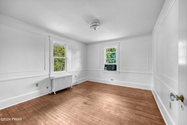 unfurnished room with radiator, crown molding, cooling unit, and wood-type flooring