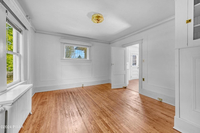 spare room featuring light hardwood / wood-style flooring, radiator, and crown molding